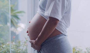 young-asian-pregnant-woman-holding-her-belly-talking-with-her-child-mom-feeling-happy-smiling-positive-peaceful-while-take-care-baby-pregnancy-near-window-living-room-home